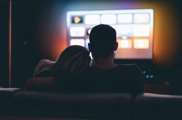 (Beispielbild) Paar im dunklem Raum schaut Fernseher